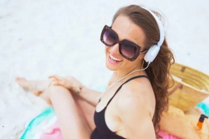 šťastná žena středního věku na bílé pláži poslouchá hudbu - mature woman beach bag - stock snímky, obrázky a fotky