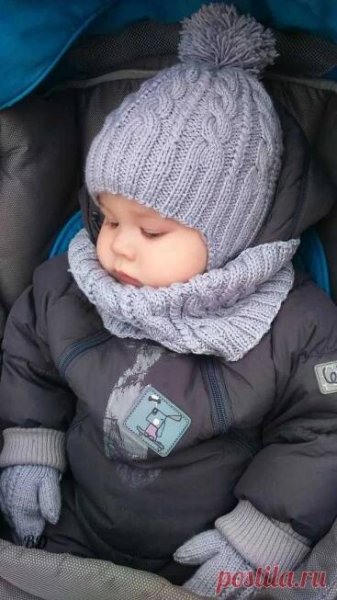 a baby in a stroller wearing a winter coat and hat with a scarf around it's neck