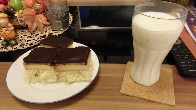 there is a piece of cake and a glass of milk on the table next to it