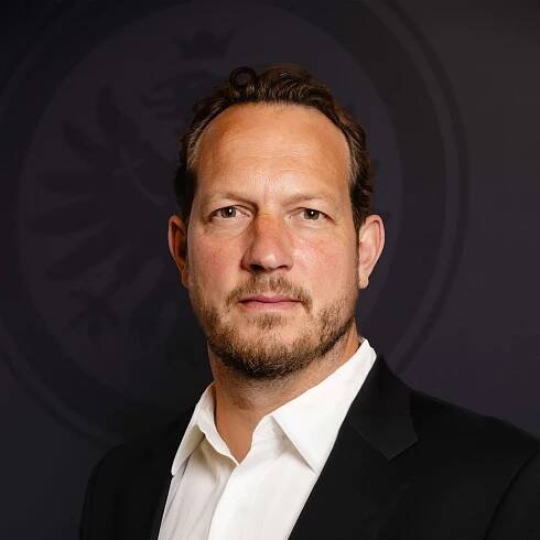 Portrait von Jan Schneider, vor einem Hintergrund mit Eintracht-Adler-Logo.