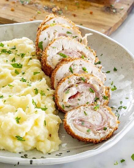 side view shot of chicken cordon bleu next to a side of mashed potatoes.