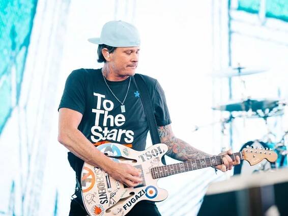 Tom DeLonge playing the guitar on stage