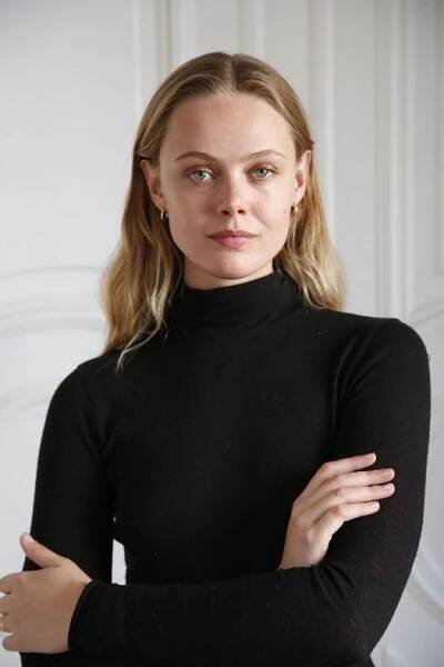 a woman wearing a black turtle neck sweater with her arms crossed looking at the camera