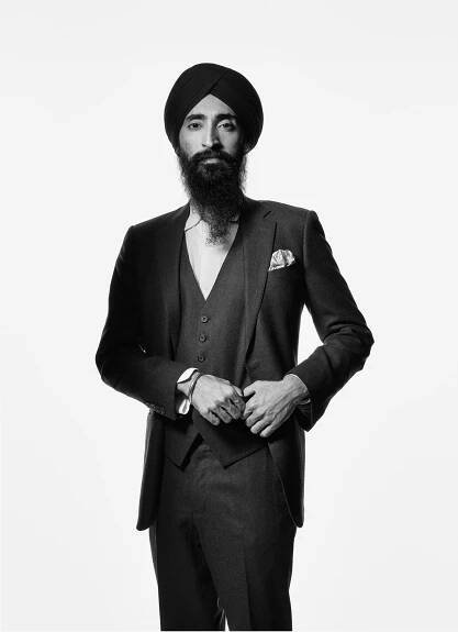 A black and white portrait of actor and designer Waris Ahluwalia. He wears a tailored suit and black turban and stares confidently at the camera. 