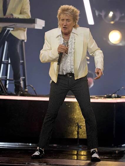 Rod Stewart performing on stage with a microphone in hand