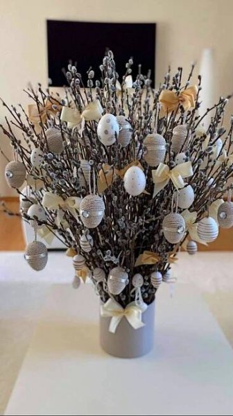 a vase filled with lots of ornaments on top of a white tablecloth covered floor