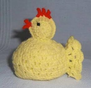 a crocheted yellow chicken sitting on top of a white surface