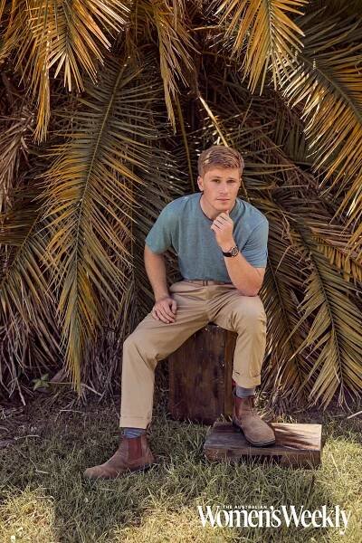 Robert Irwin sitting on a log at Australia Zoo
