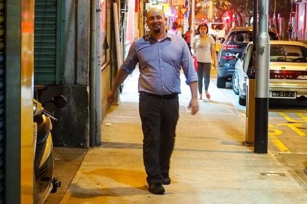 Smiling bald man walking down the sidewalk in Hong Kong