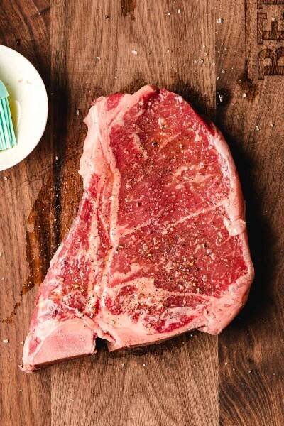 T bone steak brushed with olive oil and seasoned with salt and pepper.