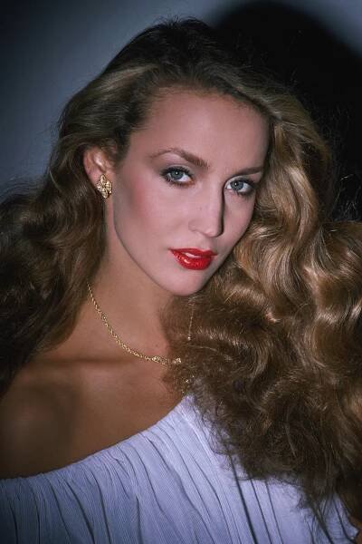 a woman with long blonde hair and red lipstick posing for a photo in a white dress