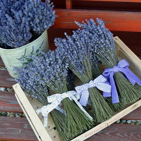 lavender flowers are arranged in baskets on a wooden crate, with ribbons tied around them