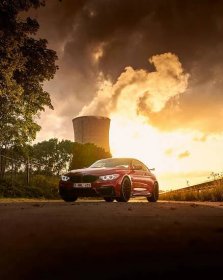 a red car parked in front of a cooling tower