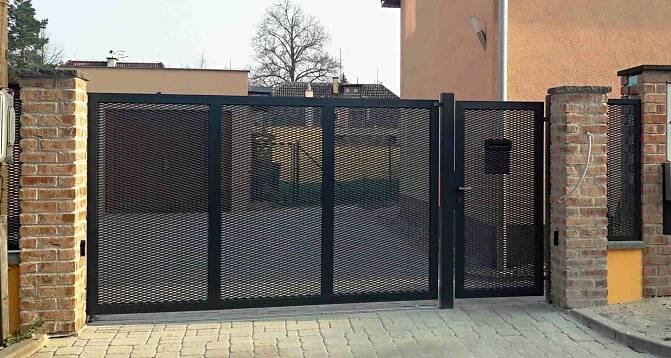 Pojezdová posuvná brána na kolejnici firmy PROWERK s výplní tahokov v kombinaci se vstupní brankou. Brána a branka v černé barvě. Zakázka byla realizována v Praze.