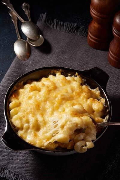 A casserole dish of mac and cheese on a grey linen napkin.