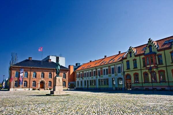 a statue in front of a building with a norwegian flag on top