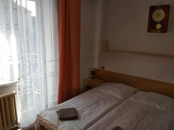 a bedroom with a bed and a window with a clock at Penzion Beta in Luhačovice