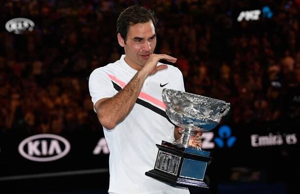 Roger Federer cries as he holds a trophy. 