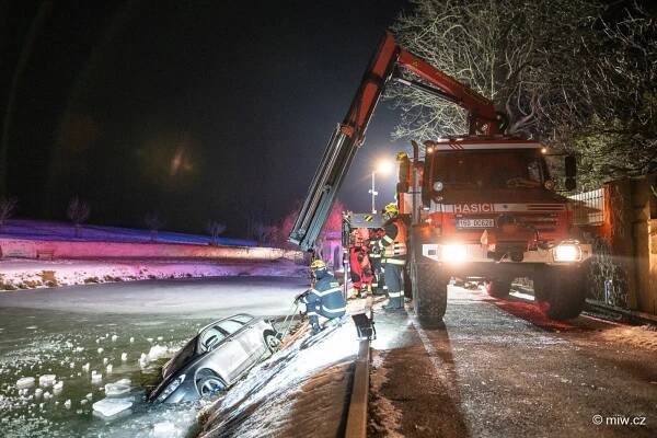 Osobní auto po nárazu do domu skončilo na boku v rybníku