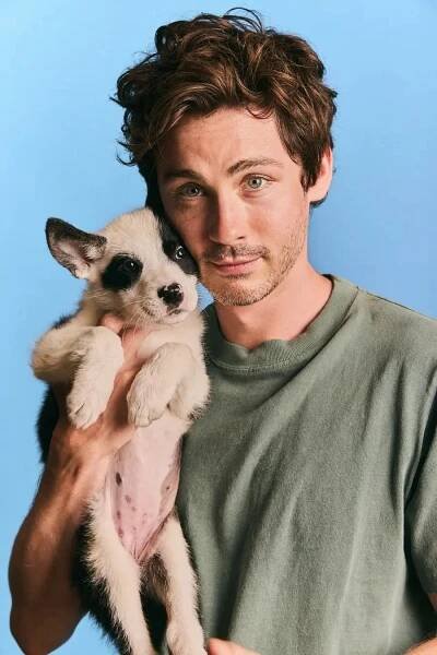 Logan holding a puppy against a plain background, wearing a casual crewneck shirt