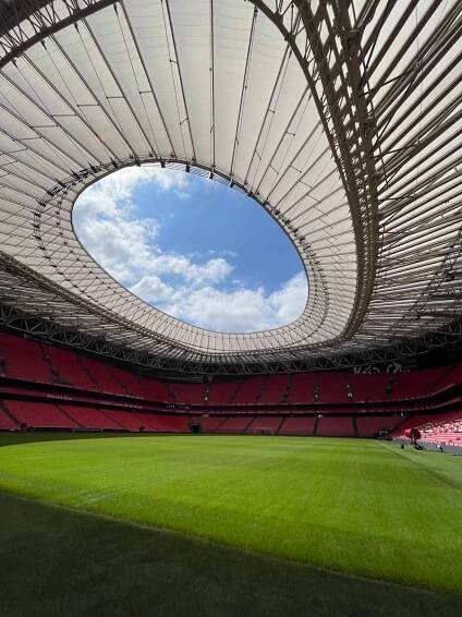 inside of the athletic bilbao stadium on a stadium tour so there are no fans or players inside, it is empty with light entering from the top onto the perfectly manicured grass.