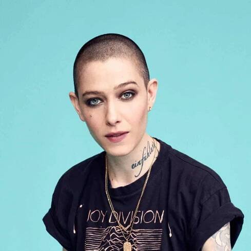 Asia Kate Dillon looks at the camera, they are a femme with a shaved head and smoking eye makeup