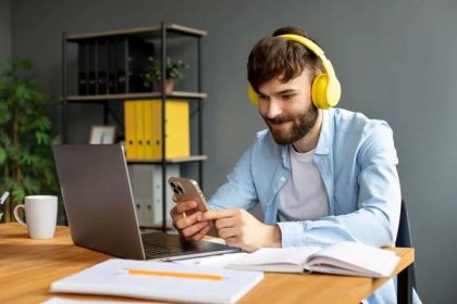 Young man listening to music on headphones while working