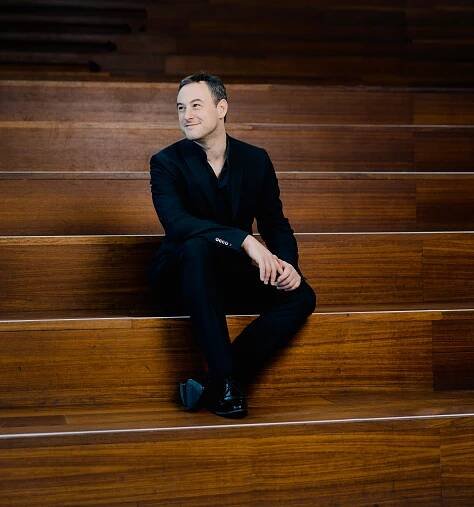 A white man smiling sitting on some large wooden steps
