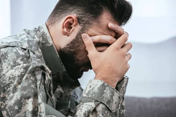 Boční pohled na depresi armádní člověka ve vojenské uniformě s posttraumatickou stresovou poruchou drží hlavu — Stock obrázek