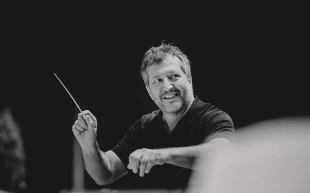 Thomas Adès with a large smile while conducting