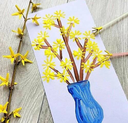 a blue vase filled with yellow flowers on top of a wooden table next to sticks