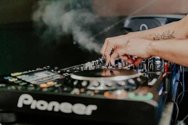 Free Close-up of a DJ mixing music on a Pioneer audio mixer in a vibrant nightclub setting. Stock Photo
