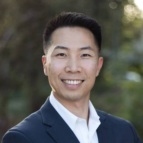 A man in a suit and white shirt is smiling for the camera.