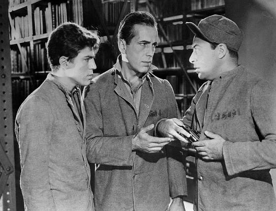 Frank Wilson (Humphrey Bogart) And Johnny Stone (Billy Halop) Take Contraband From A Fellow Prisoner In The 1939 Movie You Can'T Get Away With Murder.