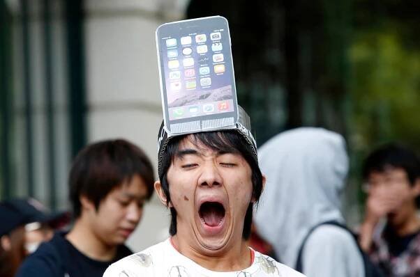 A man wearing a replica of an iPhone 6 Plus model on his head yawns while waiting for the release of Apple's new iPhone 6 and 6 Plus in Tokyo