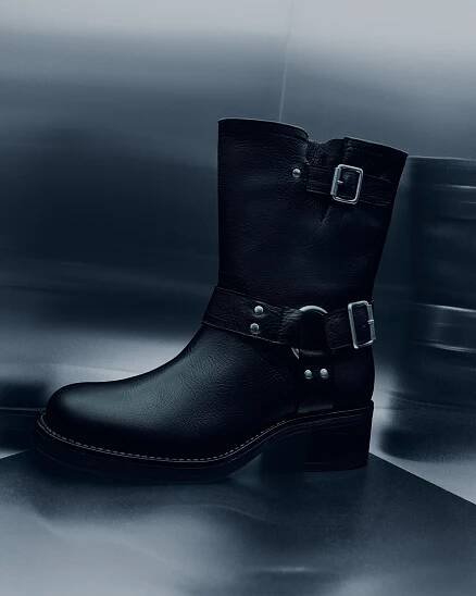 Black leather boot with buckles on a dark background