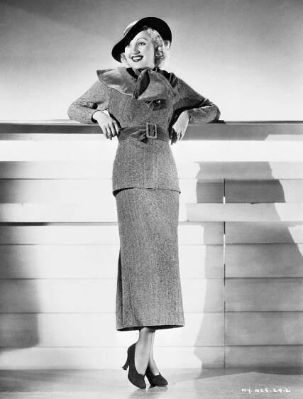 Betty Grable Wearing A Jaunty Wool Sports Dress With An Exaggerated Ascot Scarf, Wide Belt, And Stitched Felt Hat.