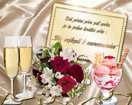 two glasses of champagne and some flowers on a table with a sign in the background
