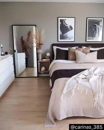 a large bed sitting in a bedroom next to two pictures on the wall above it
