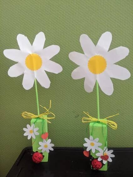 two vases with daisies and ladybugs on them are sitting on a table