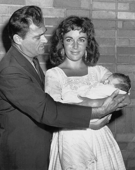 A man and a woman holding their newborn baby in 1957