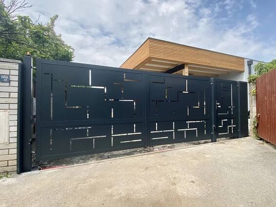 Kovový plot s designovou výplní na míru. Křídlová brána na míru s plechovou výplní s laserem vypáleným geometrickým vzorem přímek. Lakováno na antracit. Vedle brány je umístěná samostatná branka.