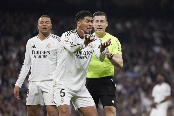 Jude Bellingham of Real Madrid CF arguing with a referee during a soccer match.