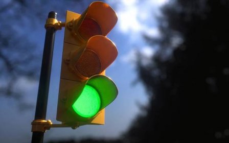 Outdoor vertical traffic light with blue sky and trees around. Traffic control concept image with shallow depth of field. — Stock Image