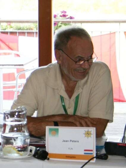 Photo of Jean Peters at a meeting with a name card in front of him