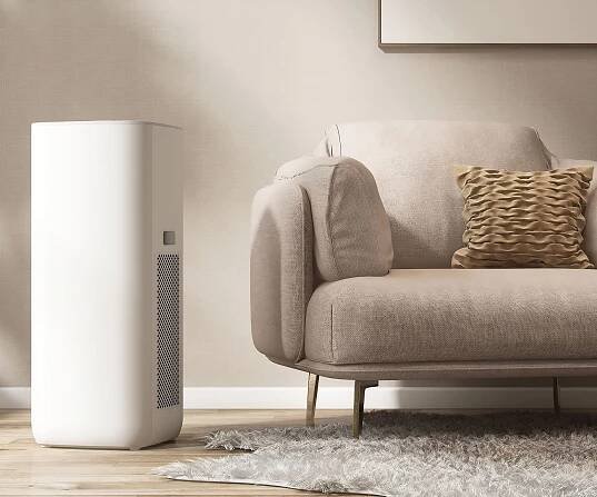 A dehumidifier in a lounge next to a sofa