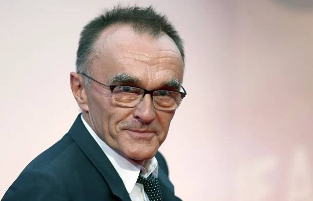 a man wearing glasses and a suit looks at the camera