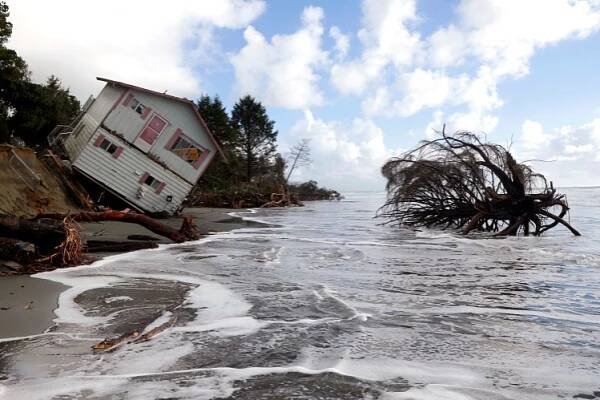 a house that has fallen into the ocean with a yellow sign on the side