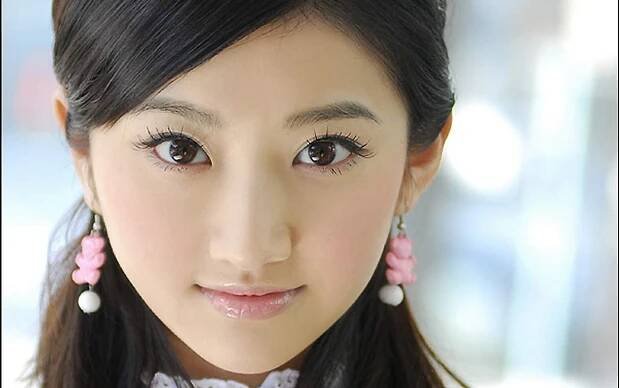 Close-up of actress Jing Tian, showcasing her striking features and large expressive eyes. She wears pink earrings and has a soft, elegant hairstyle, conveying a youthful charm.
