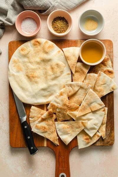 Ingredients to make air fryer pita chips arranged on a wooden board.